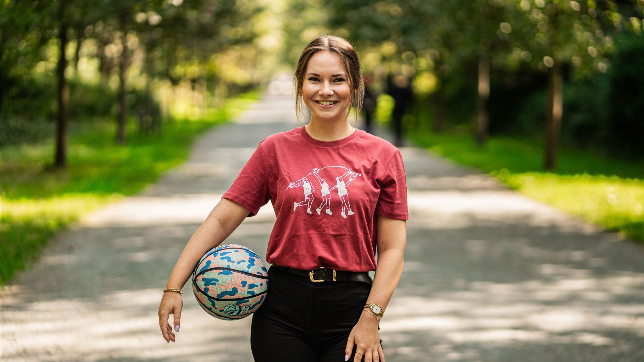 Woman with a basketball wearing a red T-shirt with a basketball drawing